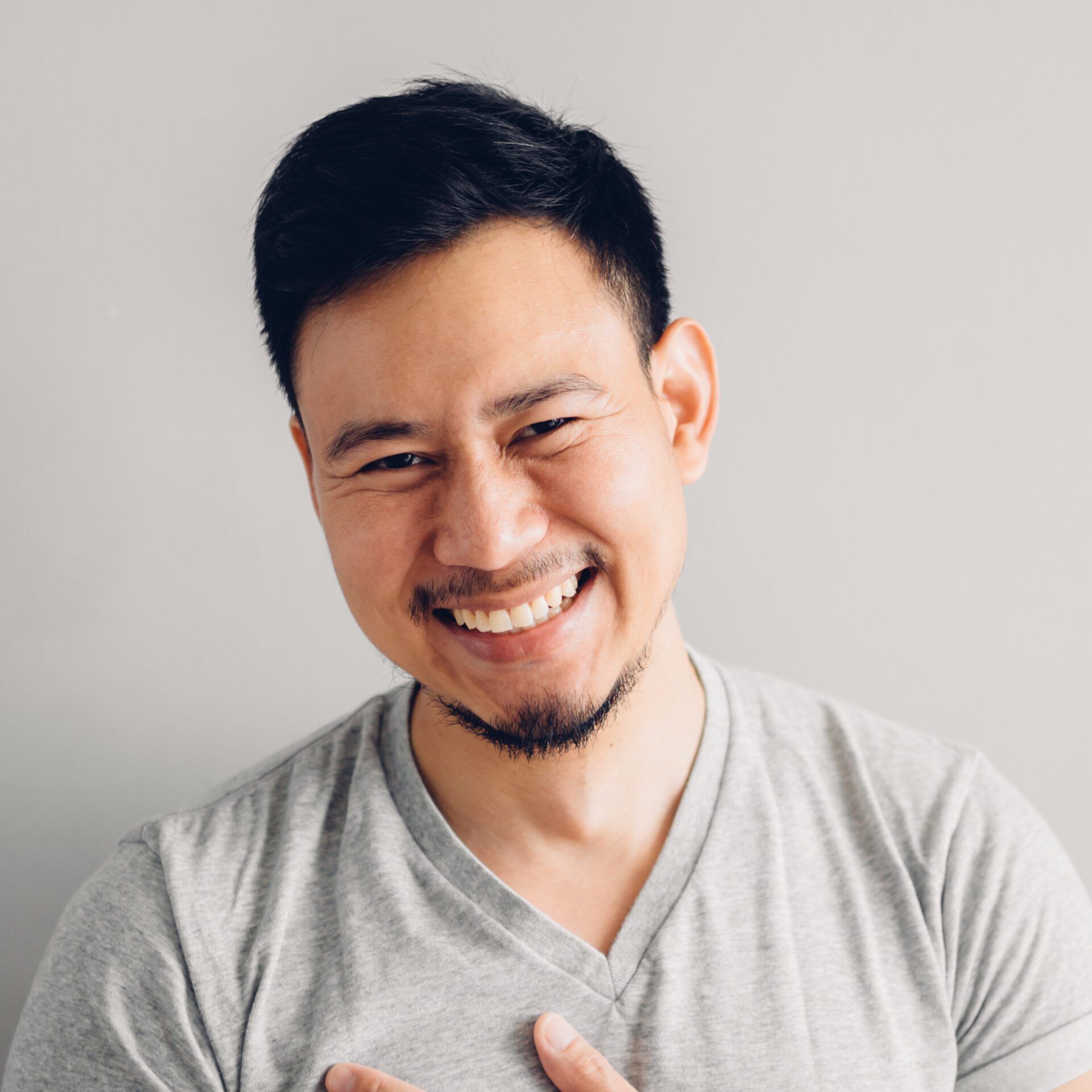 Headshot photo of Asian man with laugh face. on grey background.